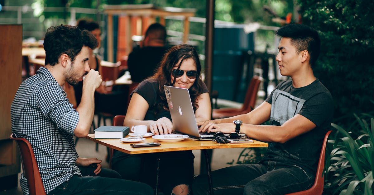 A group of people are sitting at a table using laptops.