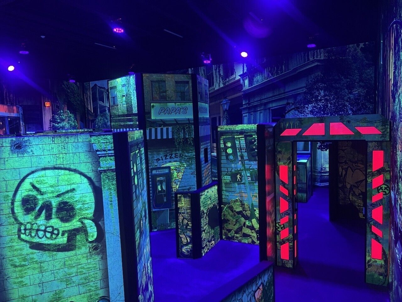 Family playing laser tag in a black light lit arena painted with uv glow inks