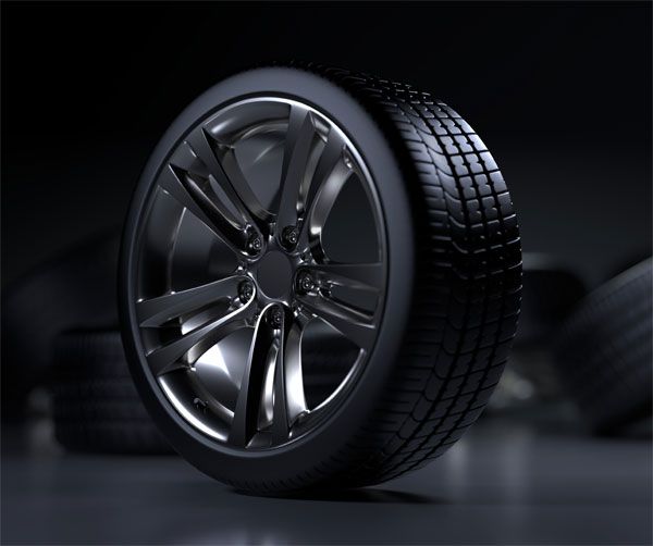 Shiny car wheel with black tire against a dark background, other tires blurred in the background. | Impact Automotive