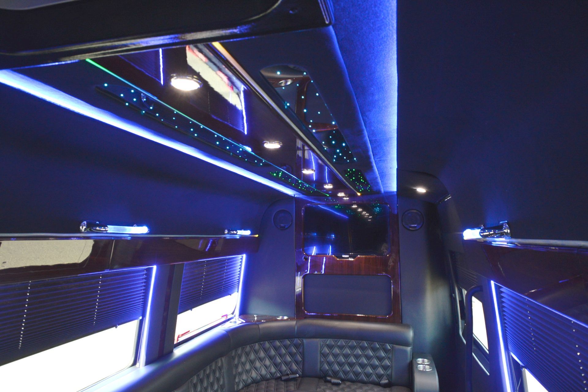 Interior of a luxury van with blue LED lighting, dark wood, and quilted seating.