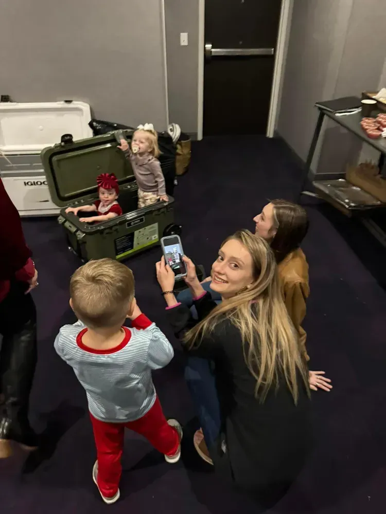 A group of people are standing around a trunk in a room.