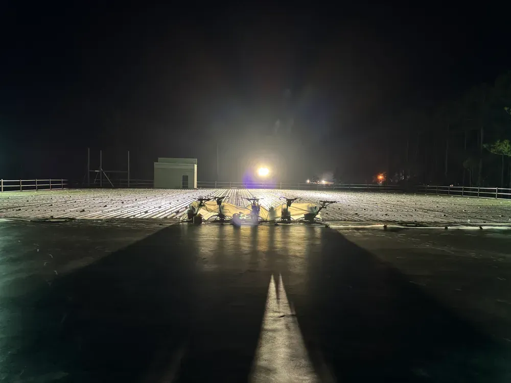 A helicopter is taking off from a runway at night.