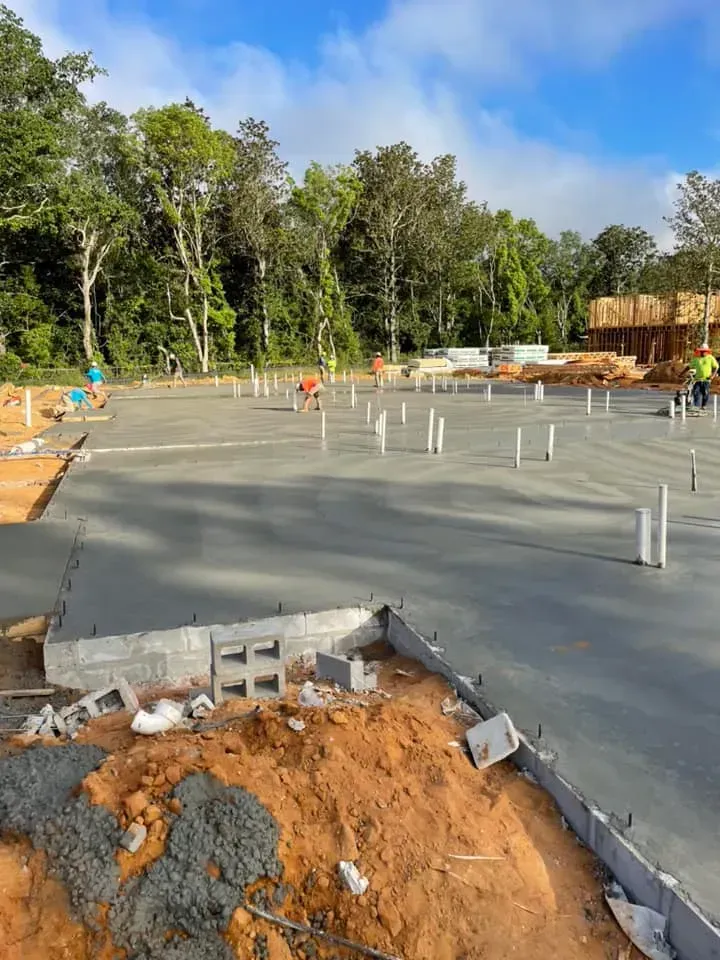A concrete floor is being built on a construction site with trees in the background.