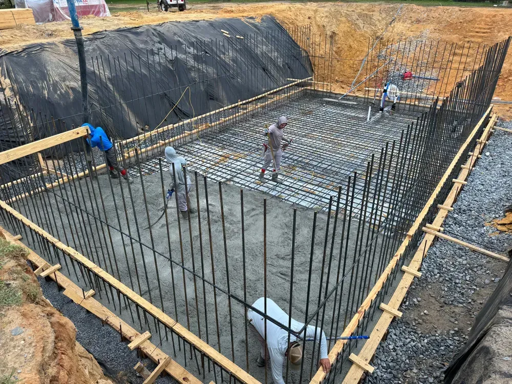 A group of construction workers are working on a large concrete pool.