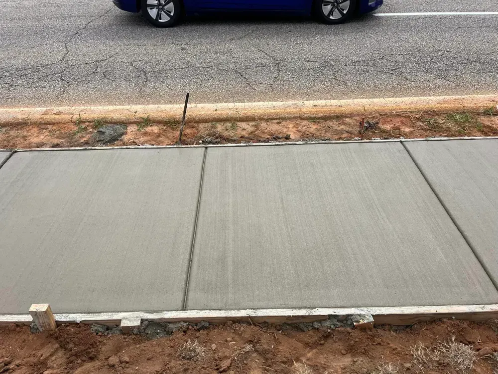 A blue car is parked on the side of the road next to a sidewalk.