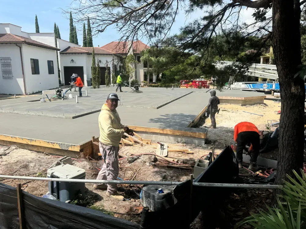 A group of construction workers are working on a concrete driveway.