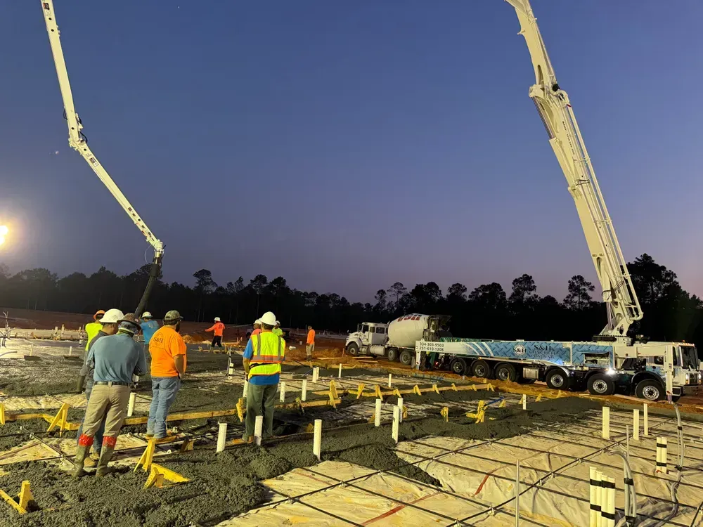 A group of construction workers are working on a construction site at night.