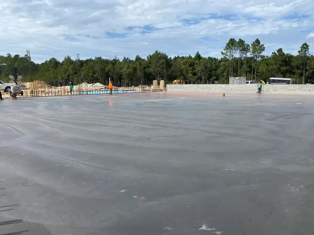 A large concrete parking lot with a lot of trees in the background.