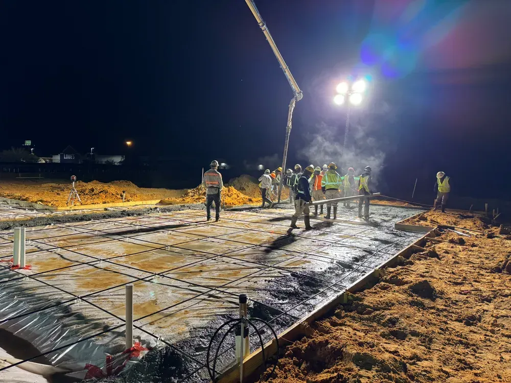 A group of construction workers are working on a construction site at night.