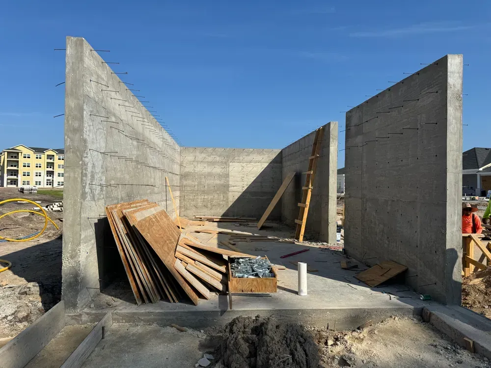 A large concrete wall is being built on a construction site.