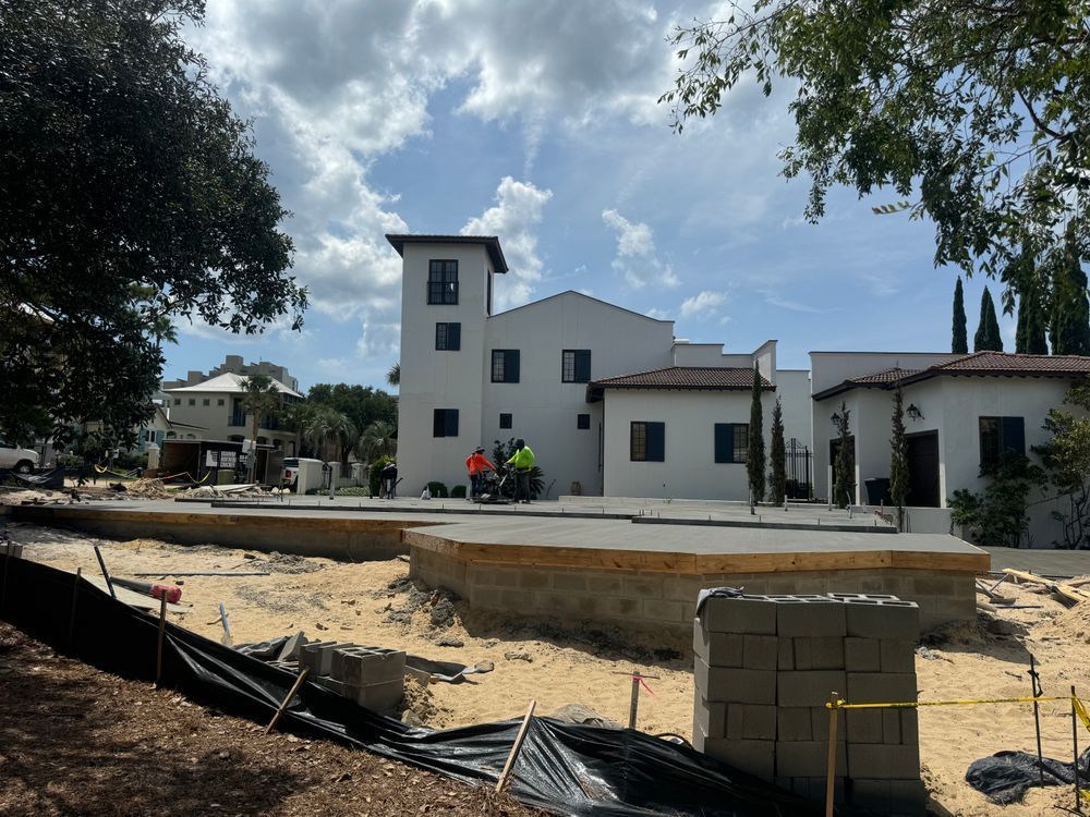 A large white building is being built in the middle of a dirt field.