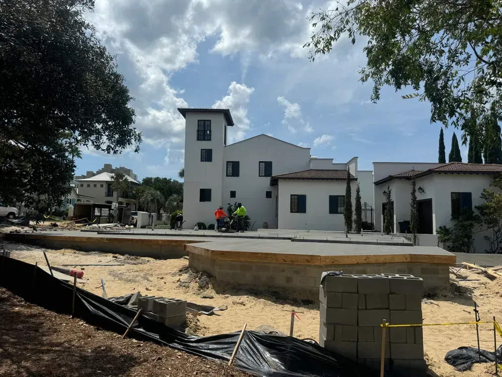 A large white building is being built in the middle of a dirt field.