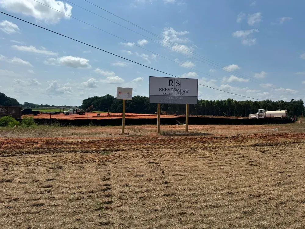 A sign that says rs on it is in the middle of a dirt field.