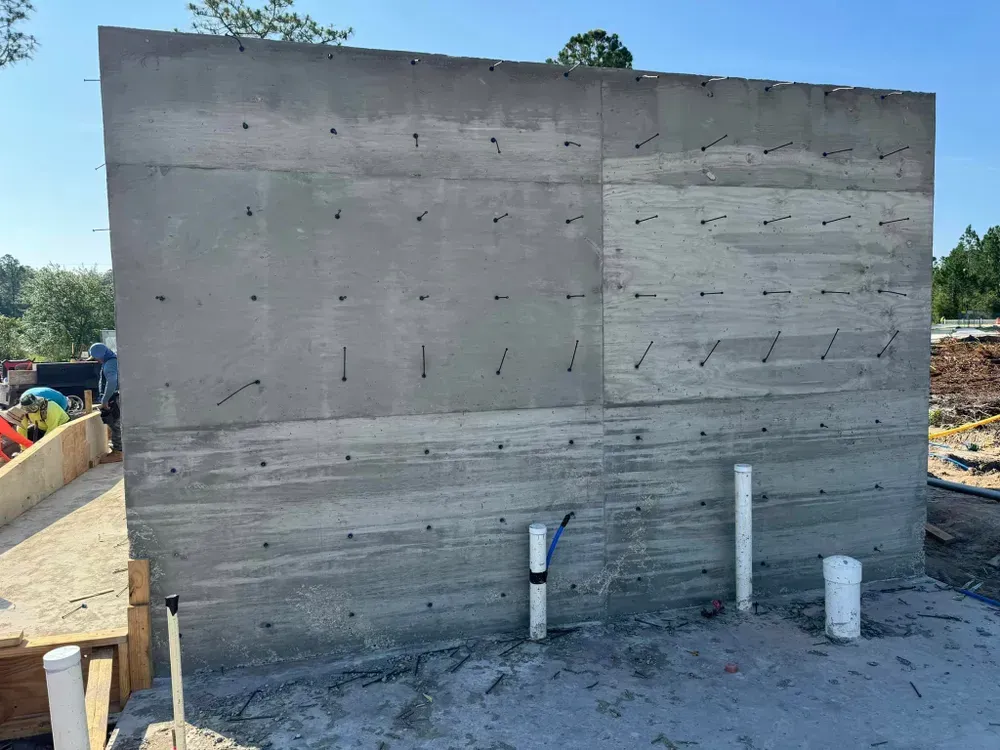 A large concrete wall is being built on a construction site.