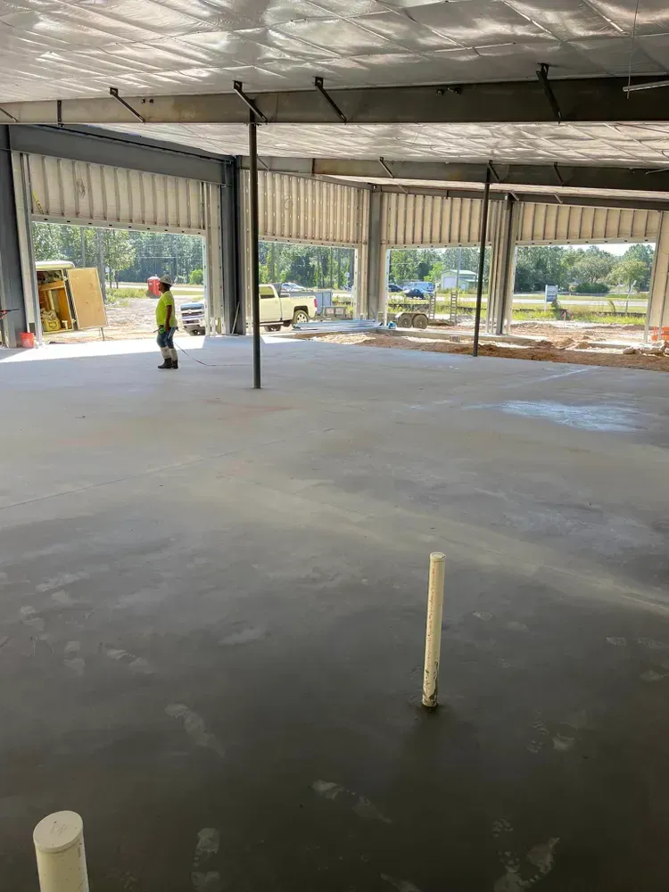 A man is standing on a concrete floor in a building under construction.