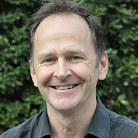 A man in a black shirt is smiling for the camera.