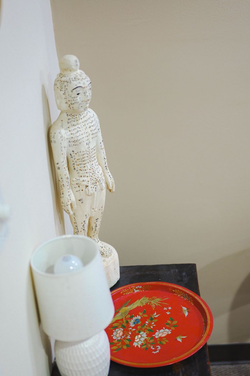 A statue of a woman is sitting on a table next to a lamp and a red plate.