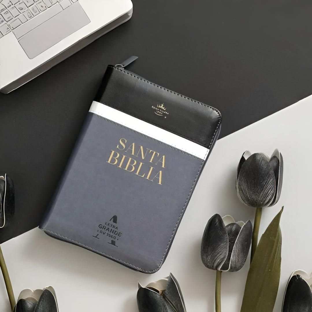 Biblia en español sobre cuaderno encuadernado en cuero con perfume y flores sobre superficie marrón.