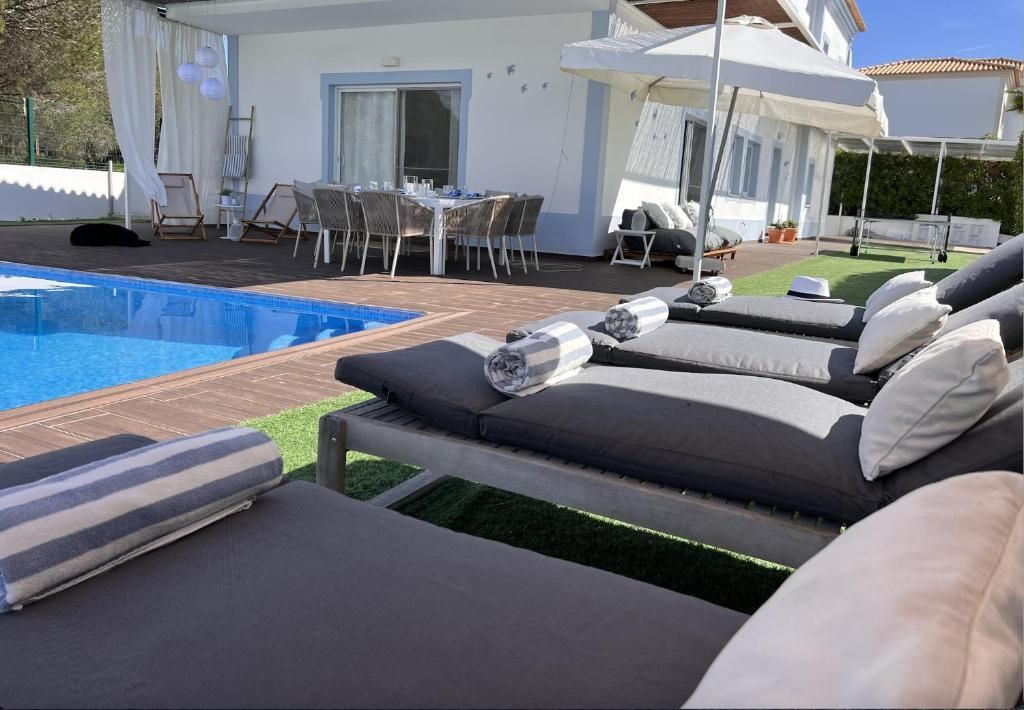 A row of lounge chairs is lined up in front of a pool.