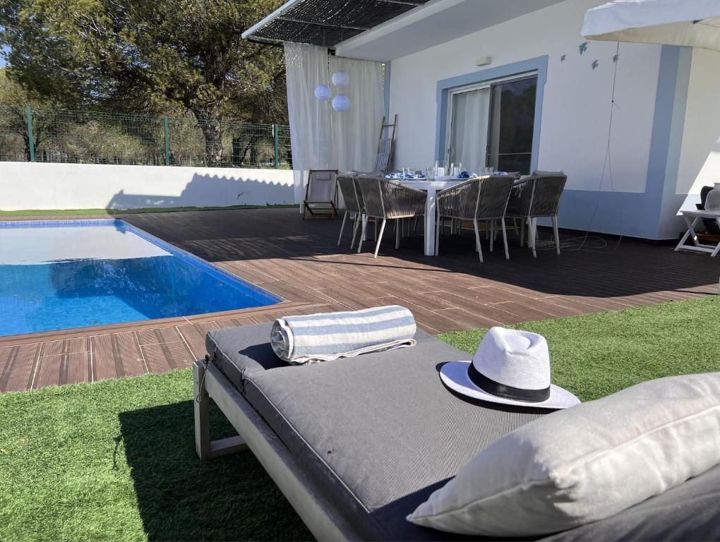 A white hat is sitting on a sun lounger in front of a swimming pool.