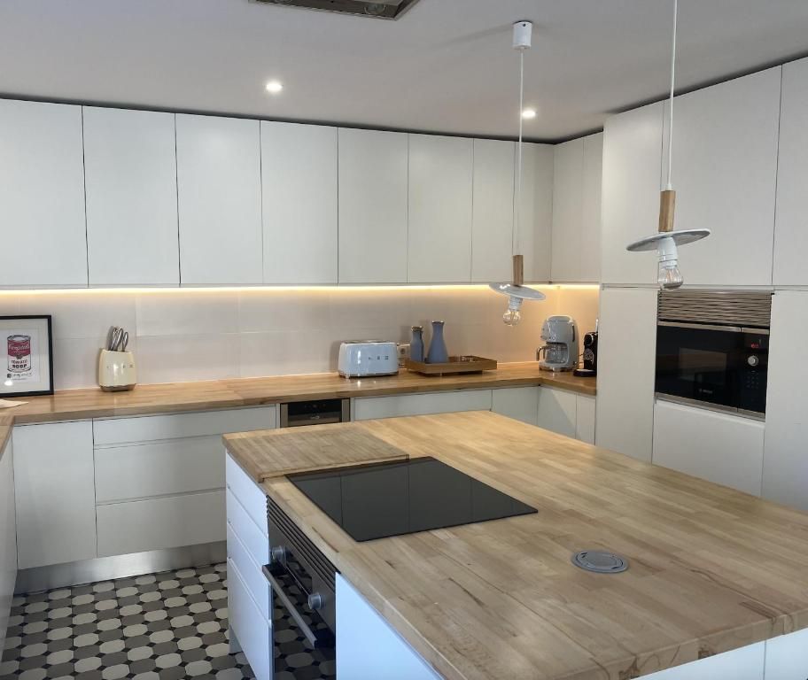 A kitchen with white cabinets and wooden countertops