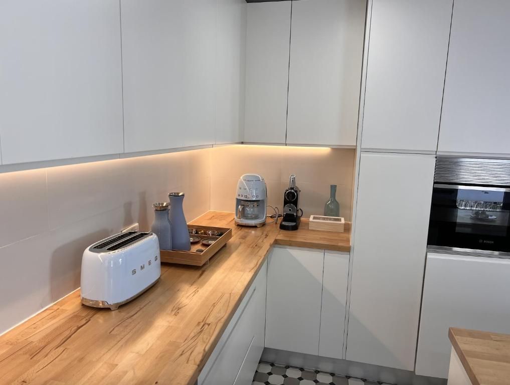 A white toaster sits on a wooden counter in a kitchen.