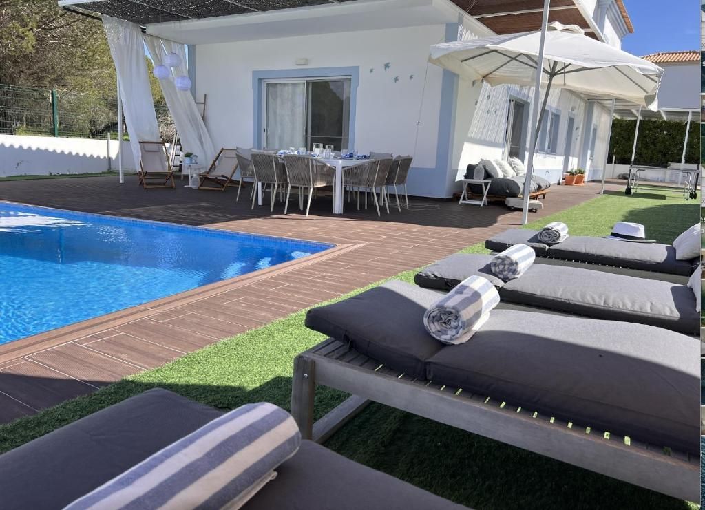 A house with a pool and sun loungers in front
