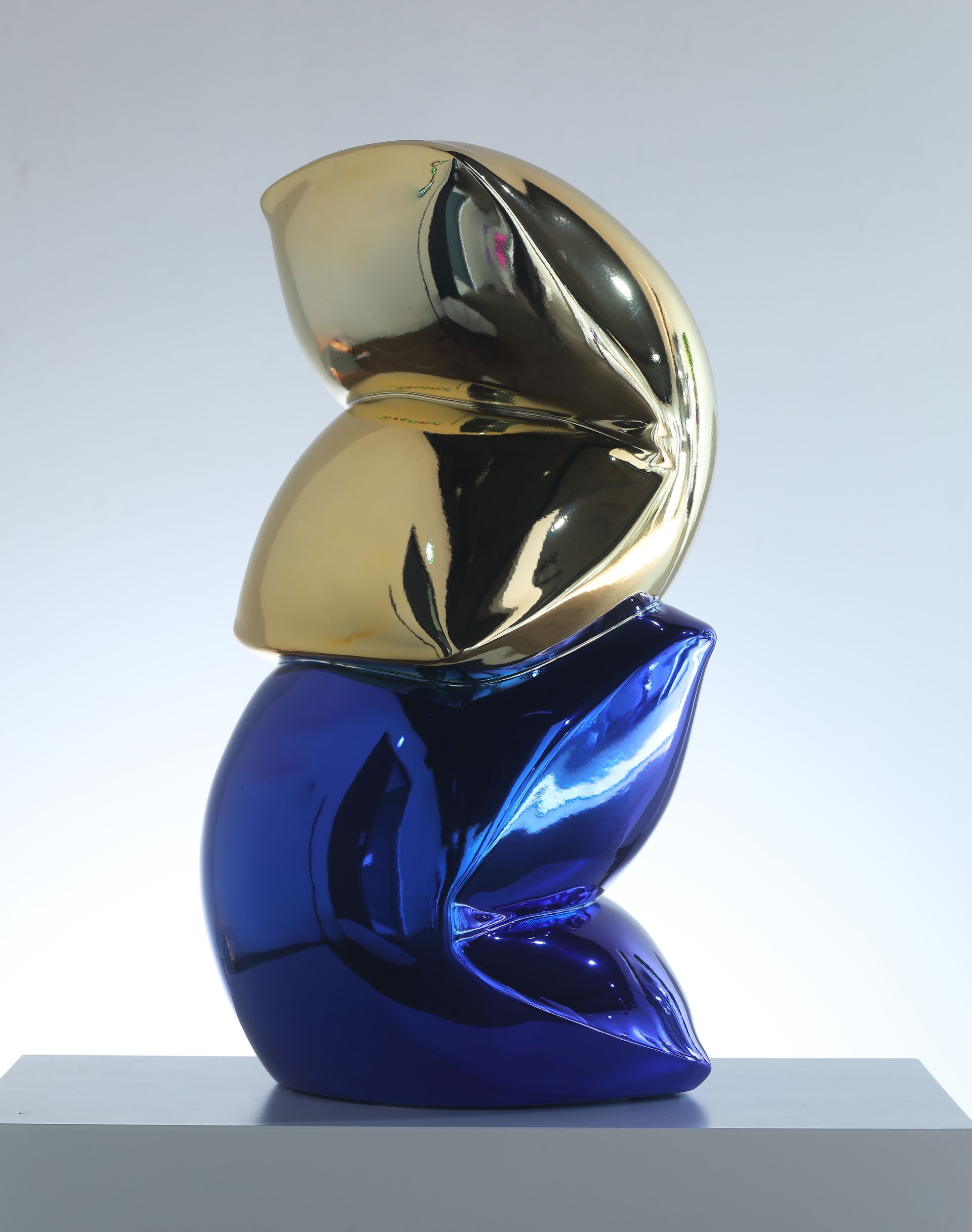 A blue and gold sculpture is sitting on a gray block