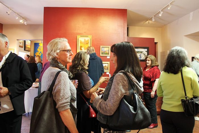 a group of people are standing in GK Fine Art Gallery in down town Santa Fe NM talking to each other.