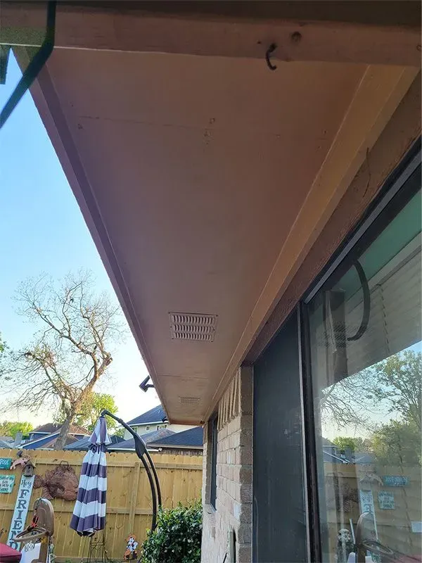 Exterior storefront awning with glass window, patio umbrella, and trees in a sunny yard
