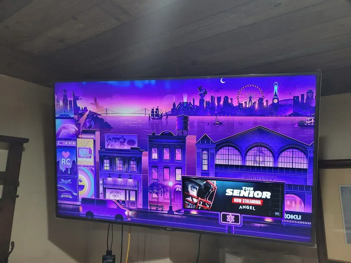 TV showing a purple cityscape game menu in a living room
