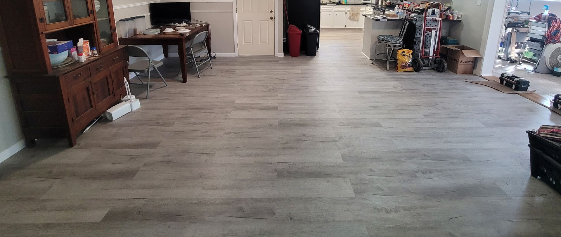 Empty living room with light wood flooring and furniture along the walls