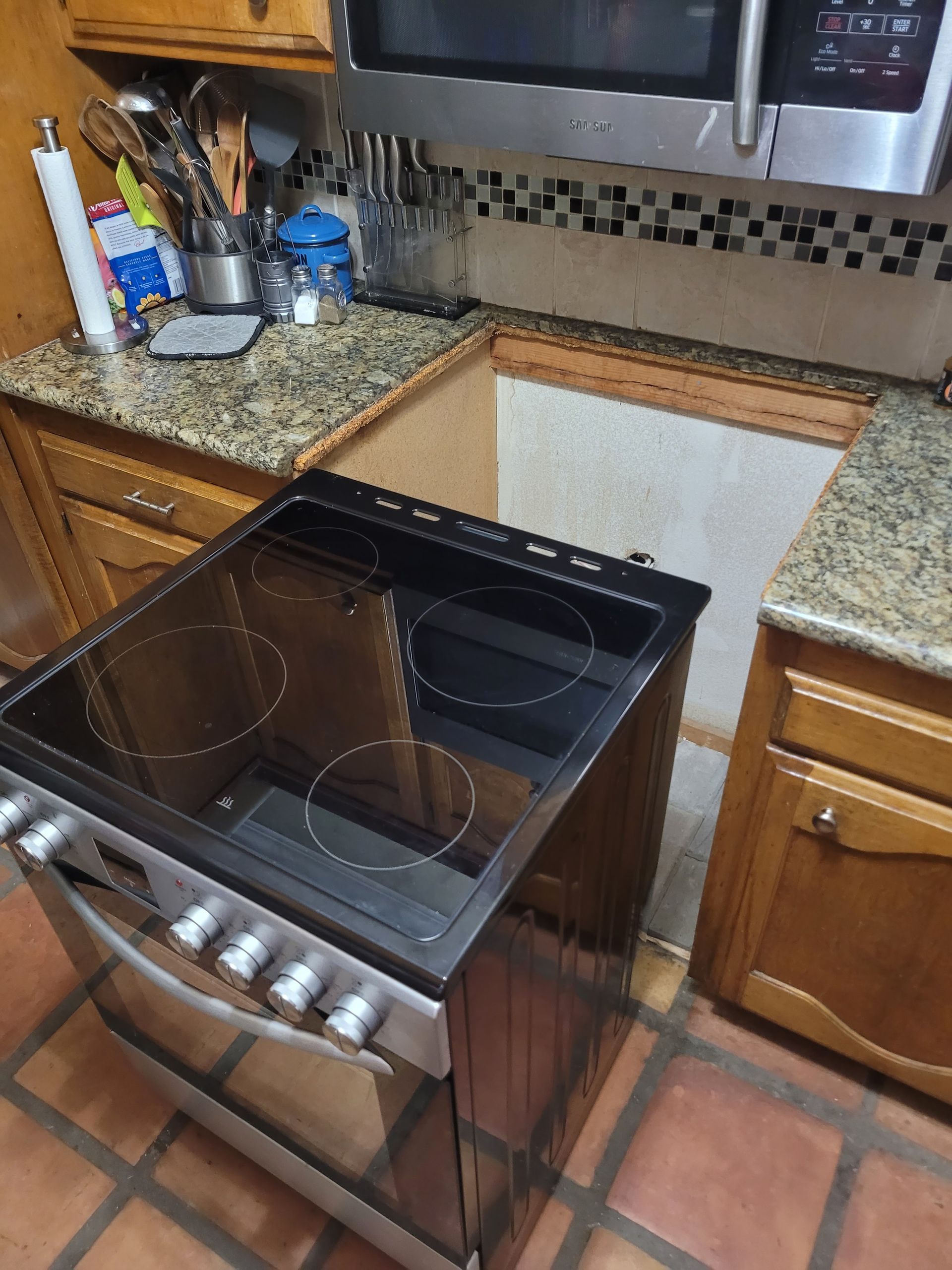Open oven door in a kitchen with granite countertops and wooden cabinets.