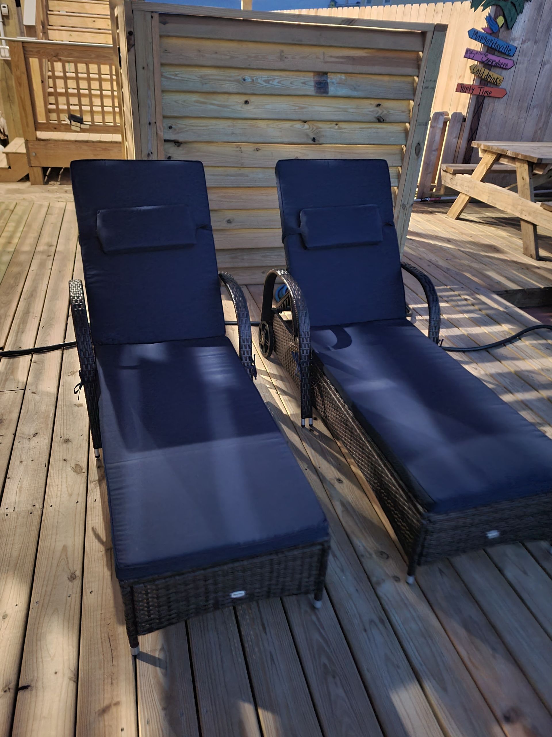 Two navy blue lounge chairs on a wooden deck in bright sunlight