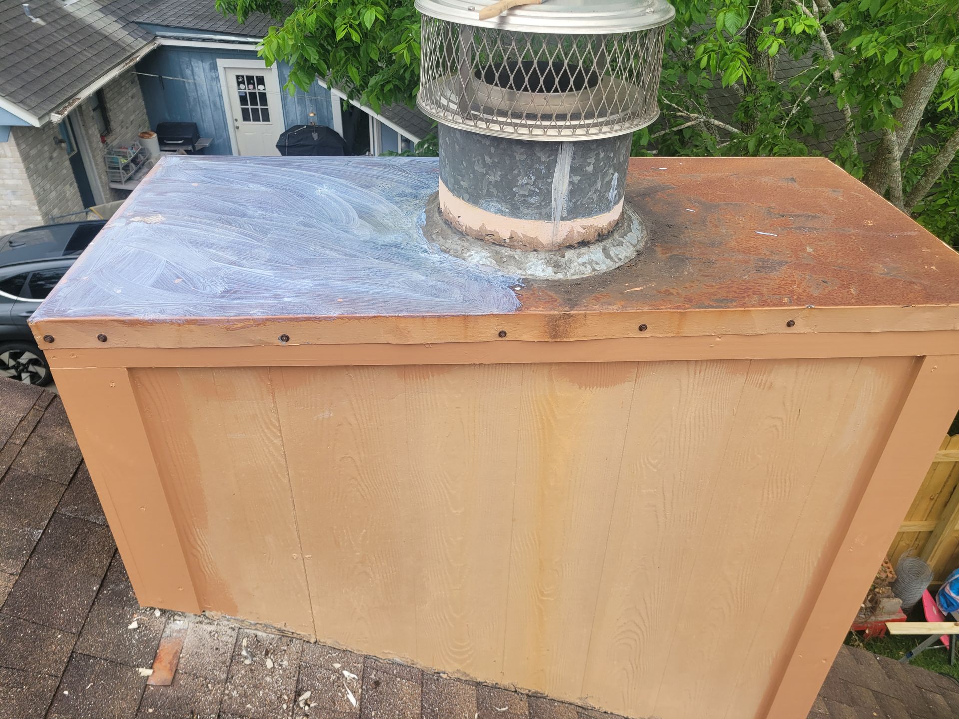Wooden rooftop utility box with metal vent and chimney cap, split silver and rusted top panel