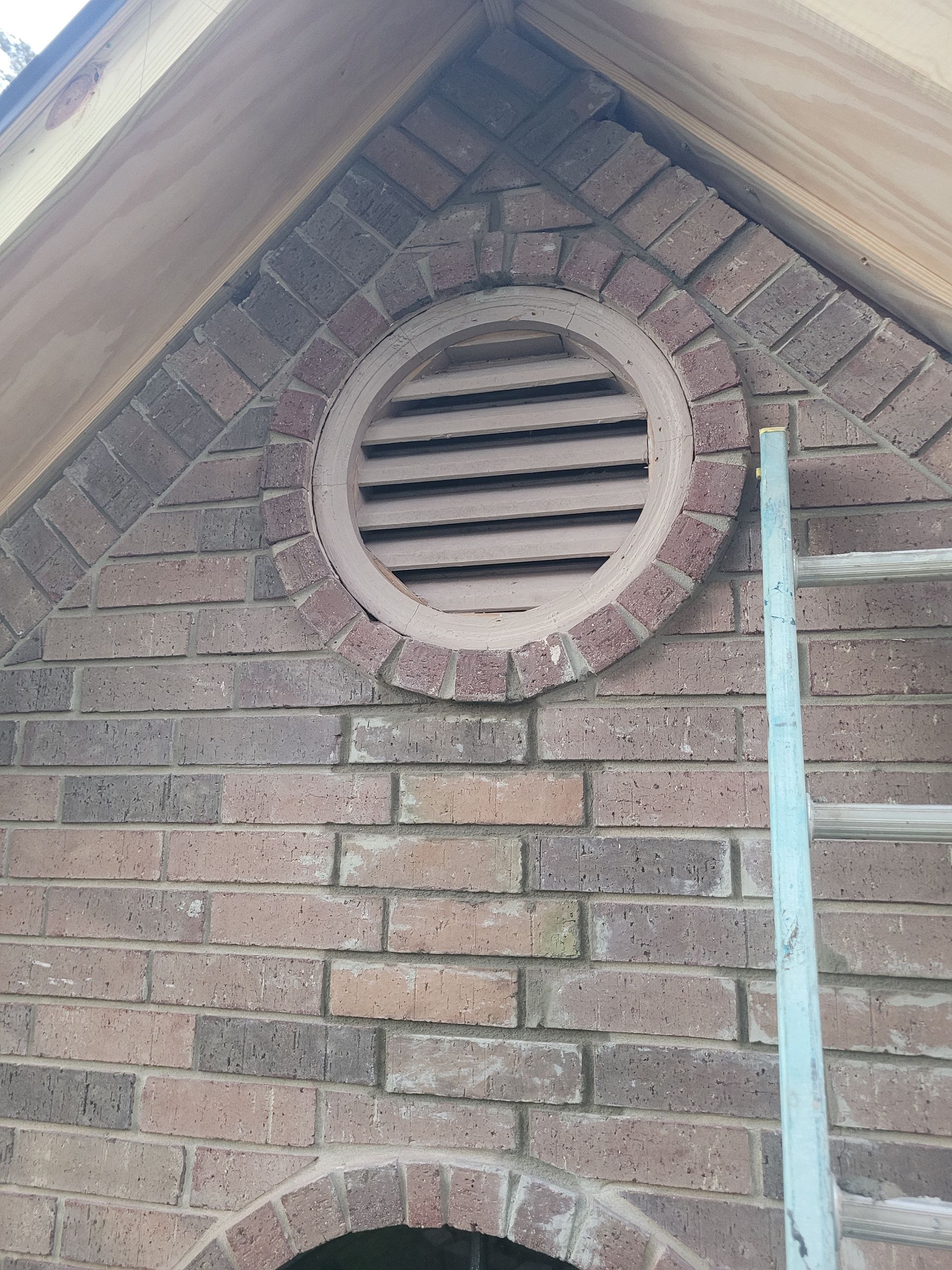 Brick exterior wall with two round vents under a sloped roofline.