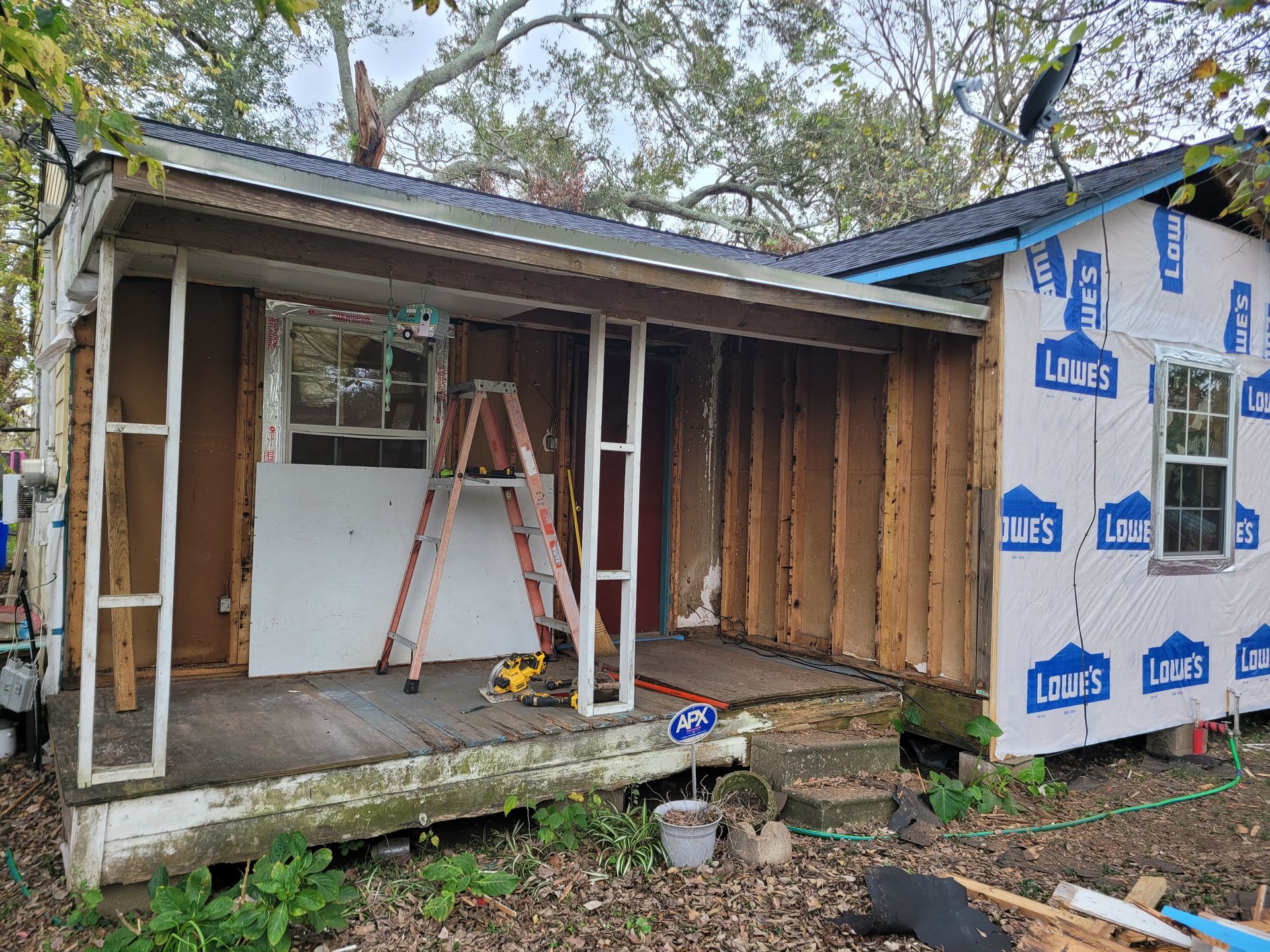 Partially renovated shed with ladder, exposed framing, and house wrap on the right side