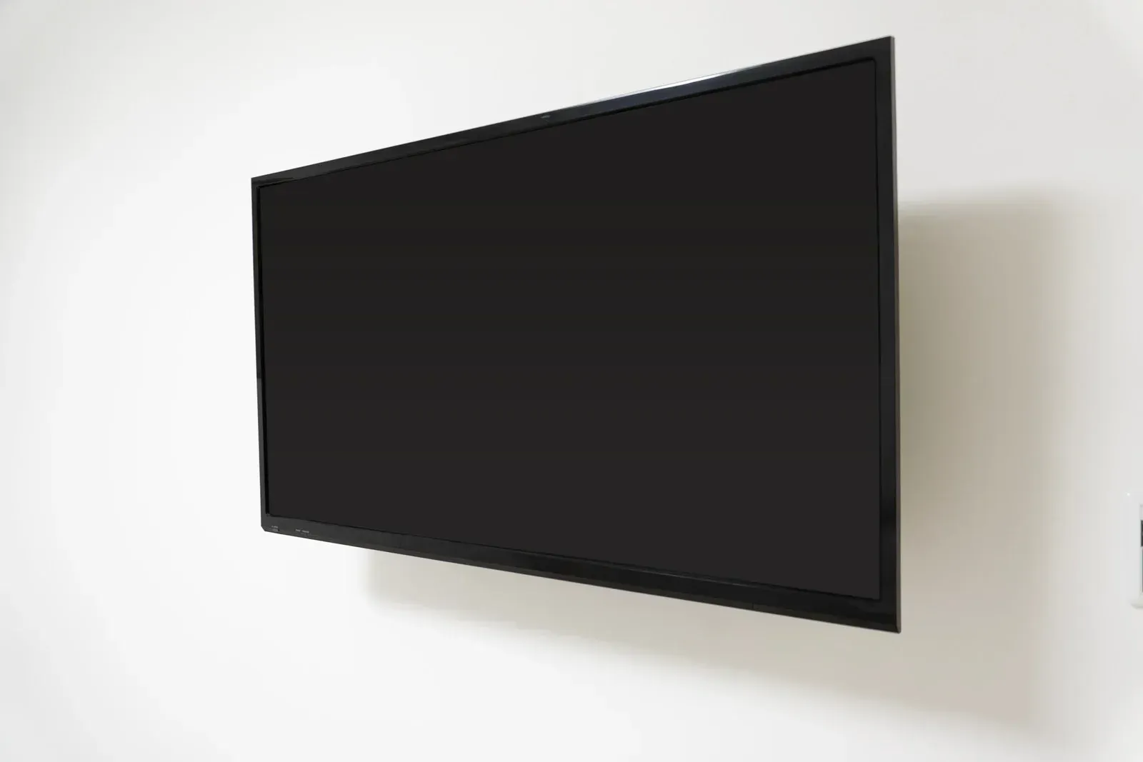 Wall-mounted black flat-screen TV on a white wall