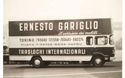 Una foto d'epoca in bianco e nero di un camion per traslochi della Ernesto Gariglio, vista laterale, con un elenco di città e servizi.