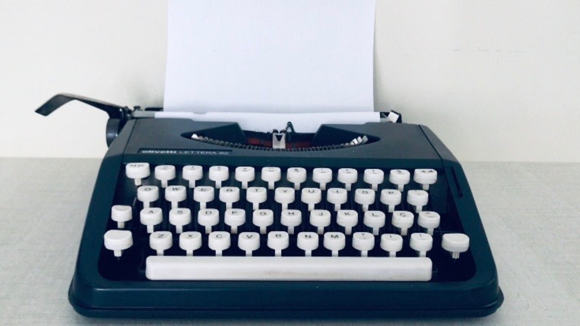 A black typewriter with white keys is sitting on a table.