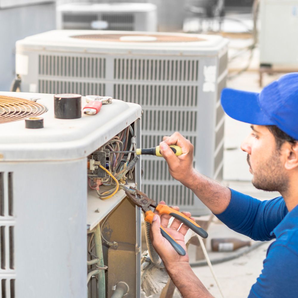 A professional electrician man is fixing the heavy unit of an air conditioner