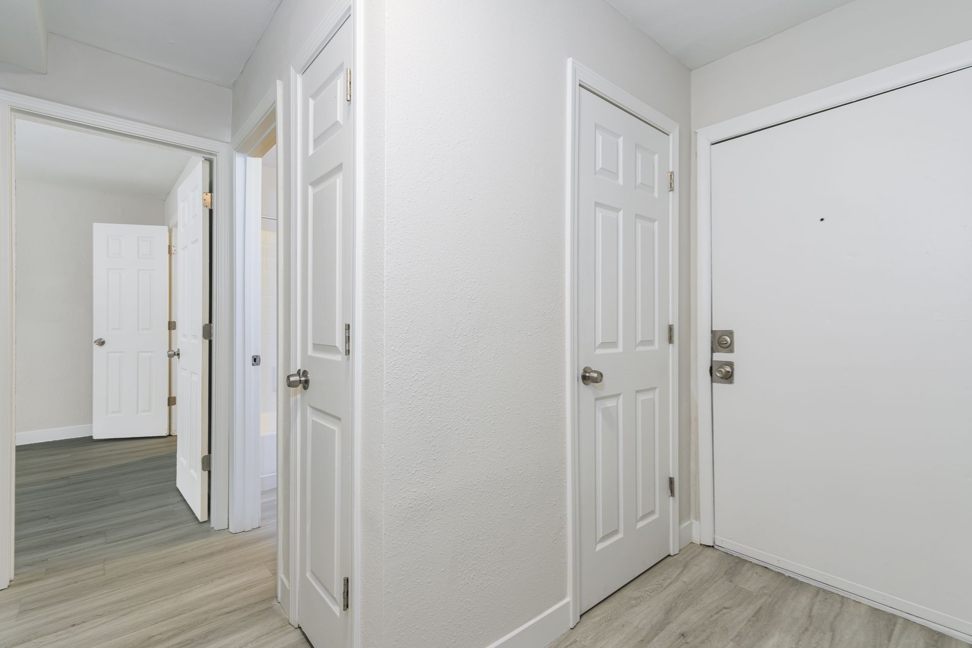 A hallway with white doors and wooden floors in a house.