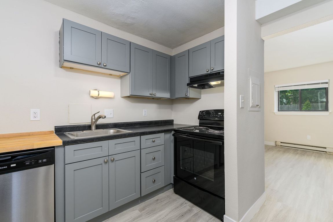 A kitchen with gray cabinets , stainless steel appliances , and a sink.