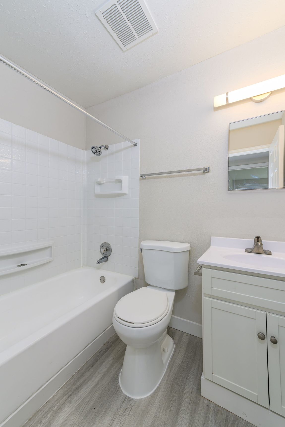 A bathroom with a toilet , sink , bathtub and mirror.