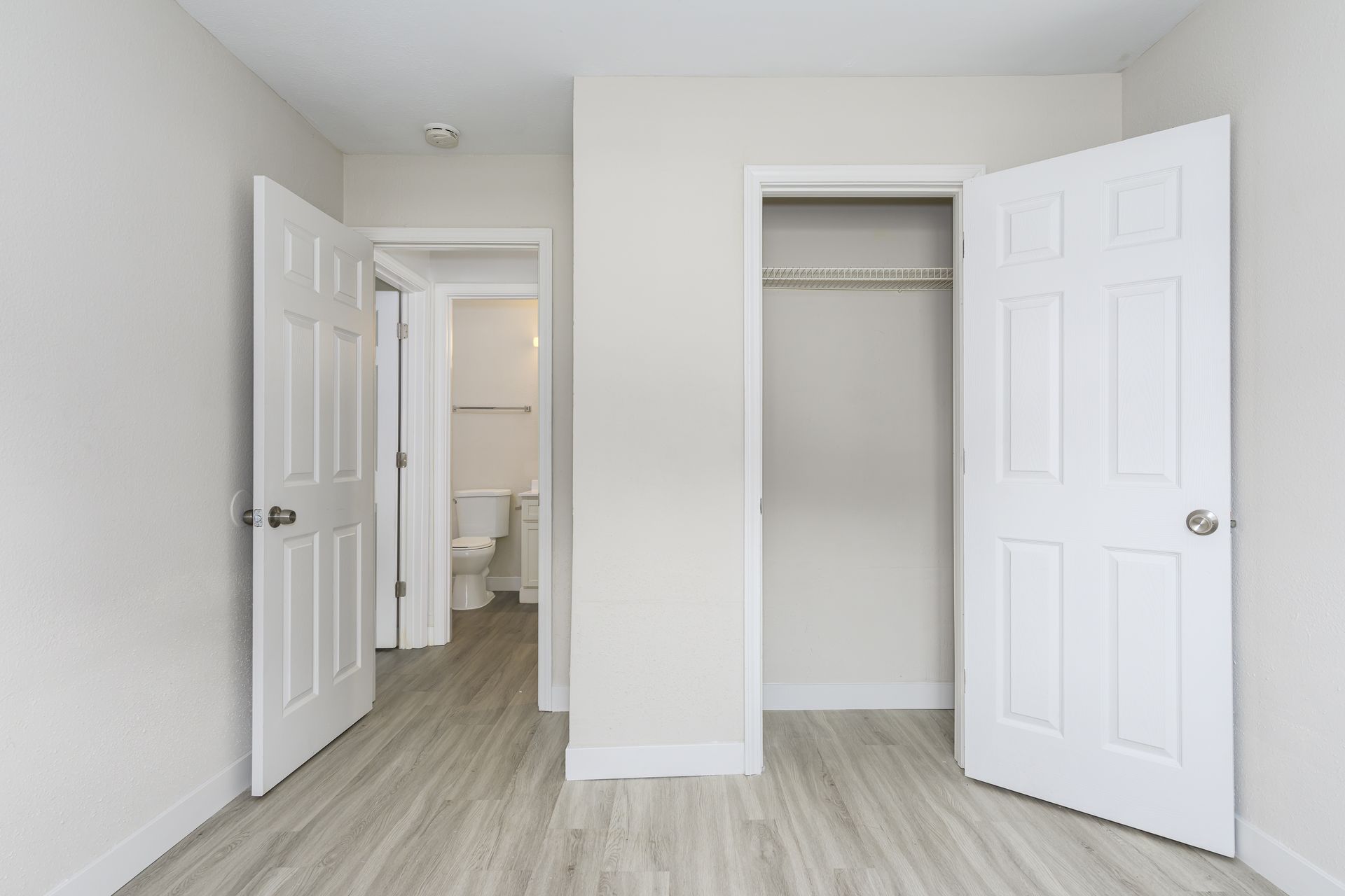 An empty bedroom with a closet and a toilet.