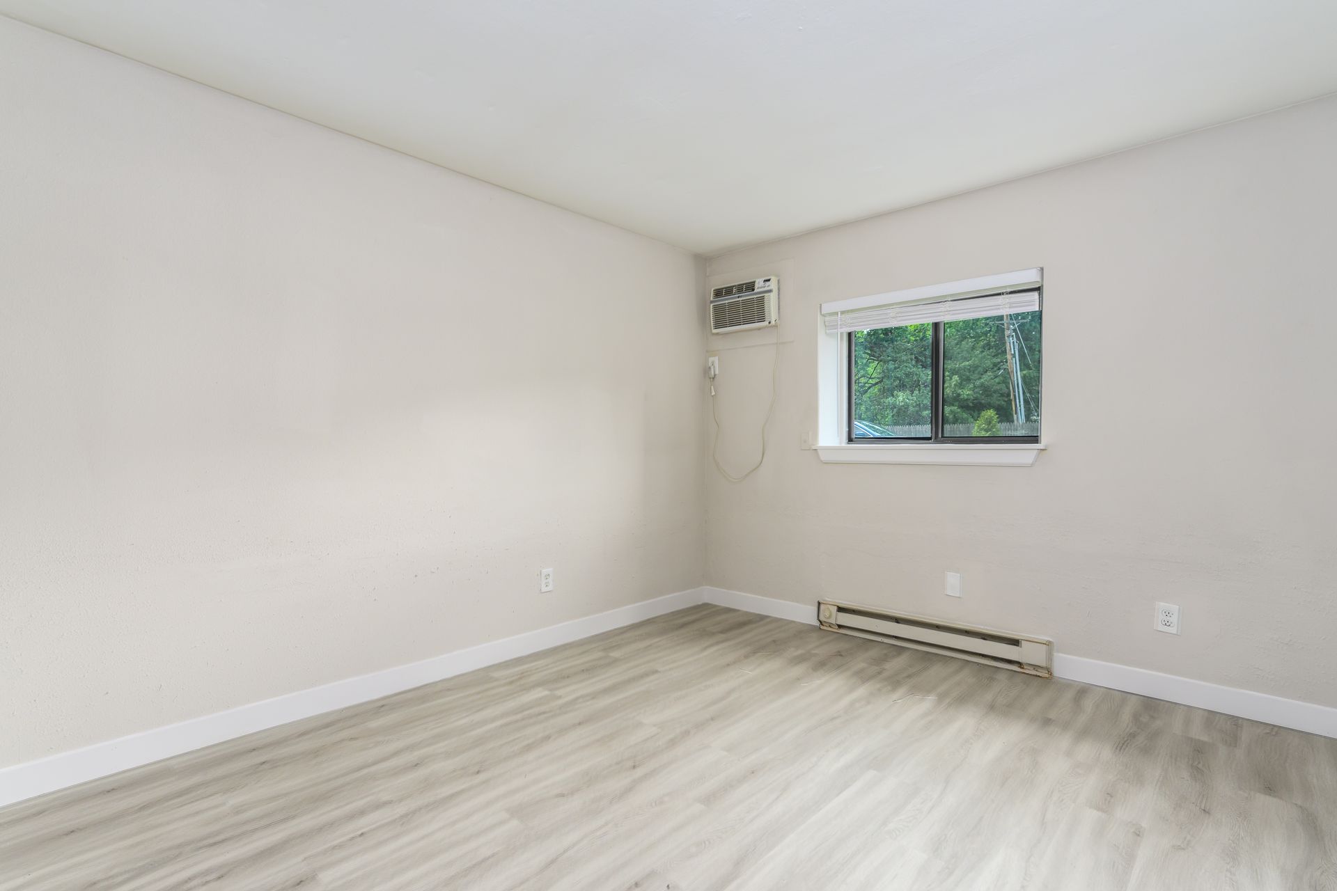 An empty room with hardwood floors and a window.
