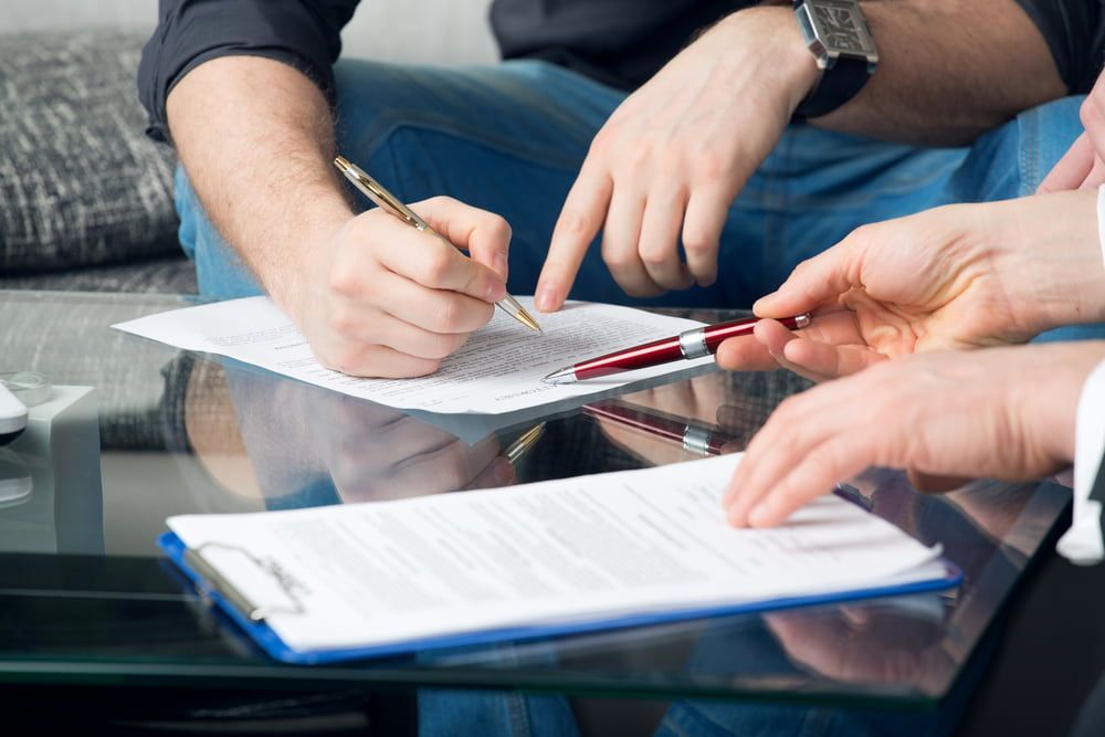 A Group Of People Are Sitting At A Table Signing A Document — Book a Vehicle Inspection in Albury, NSW