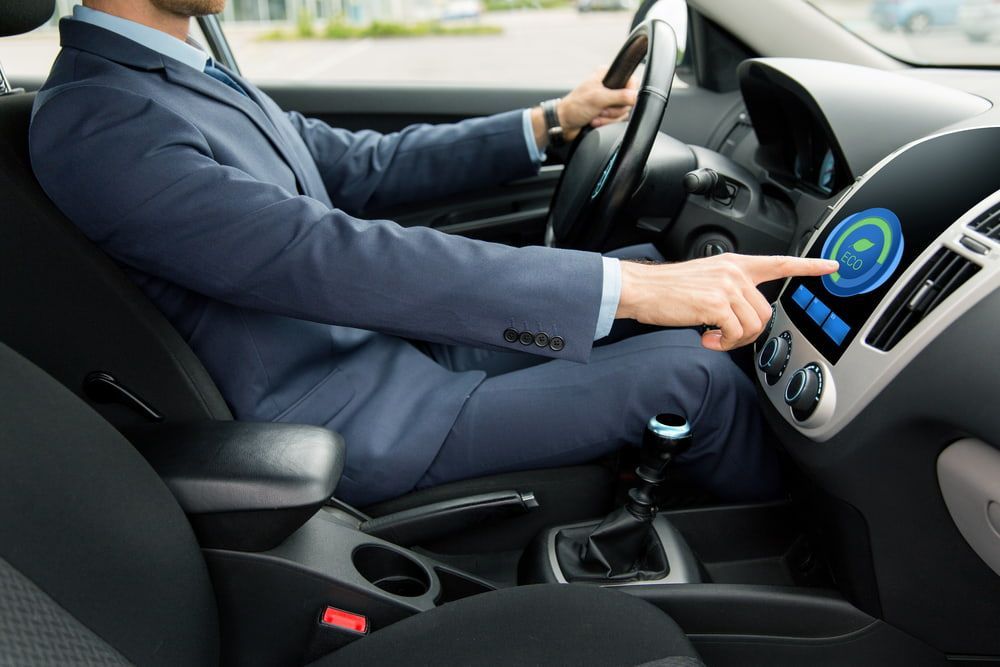 A Man In A Suit Is Driving A Car And Pressing A Button On The Dashboard — Your Experienced Mechanic in Wodonga, VIC