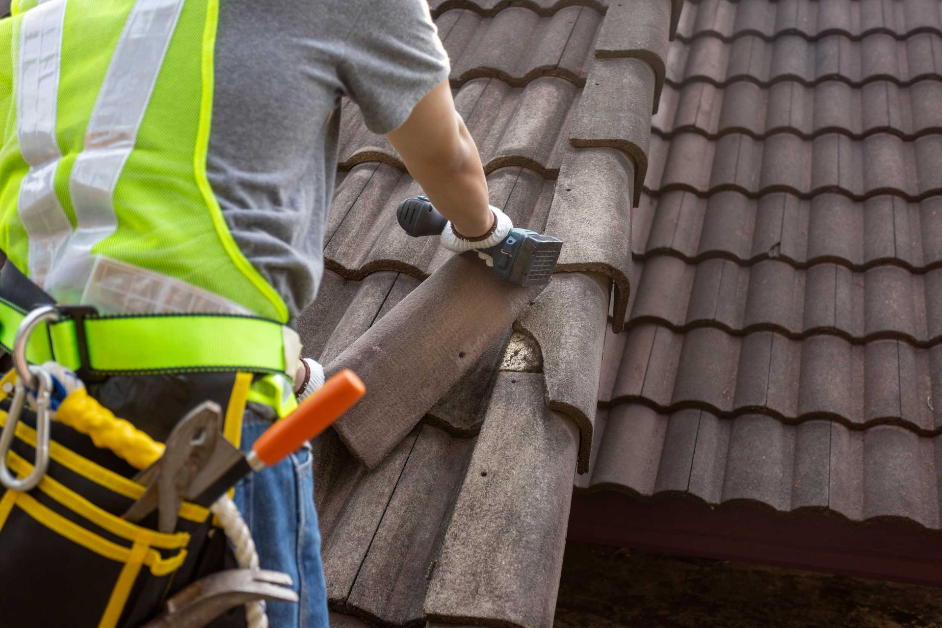 A roofer replacing damaged roof tiles during a residential roof repair.