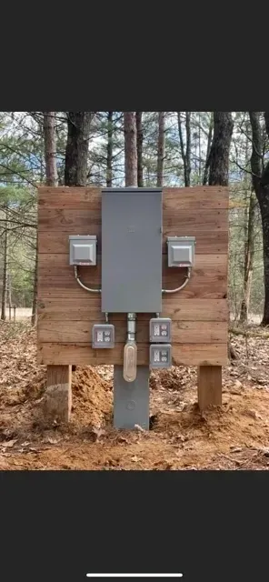 A wooden wall with electrical boxes on it in the woods.